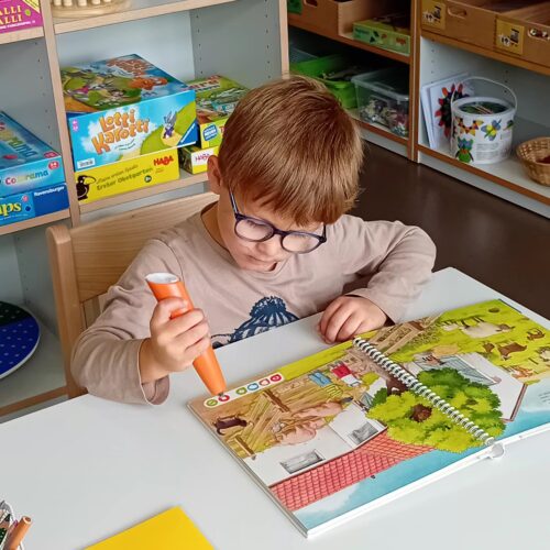 Junge hört aufmerksam auf den Tip toi Stift