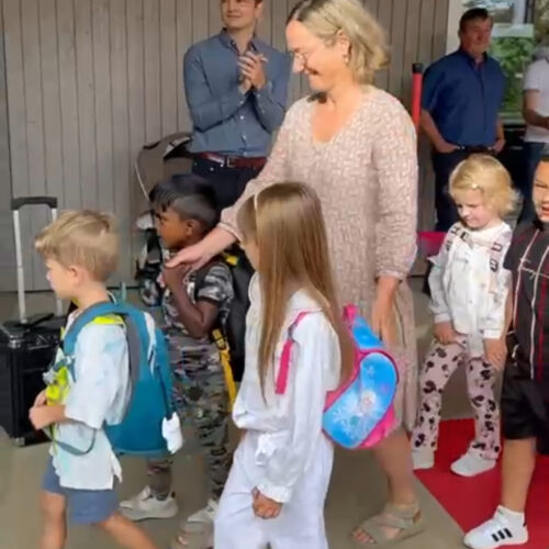 Kinder gehen mit Lehrperson über den roten Teppich