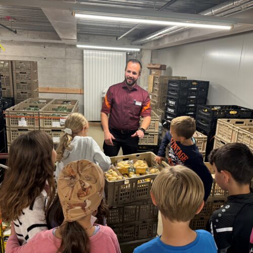 Kinder schauen in der Migros Logistik zu.