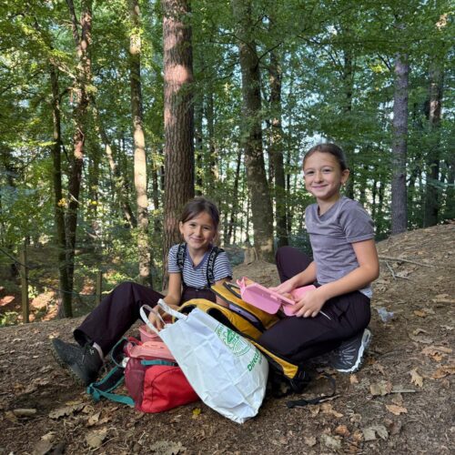 Zwei Mädchen sitzen auf dem Waldboden