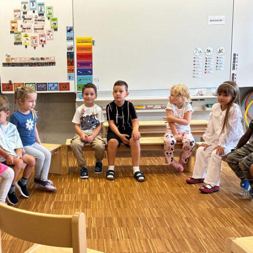 Kinder im Kindergarten sitzen auf Bänkli